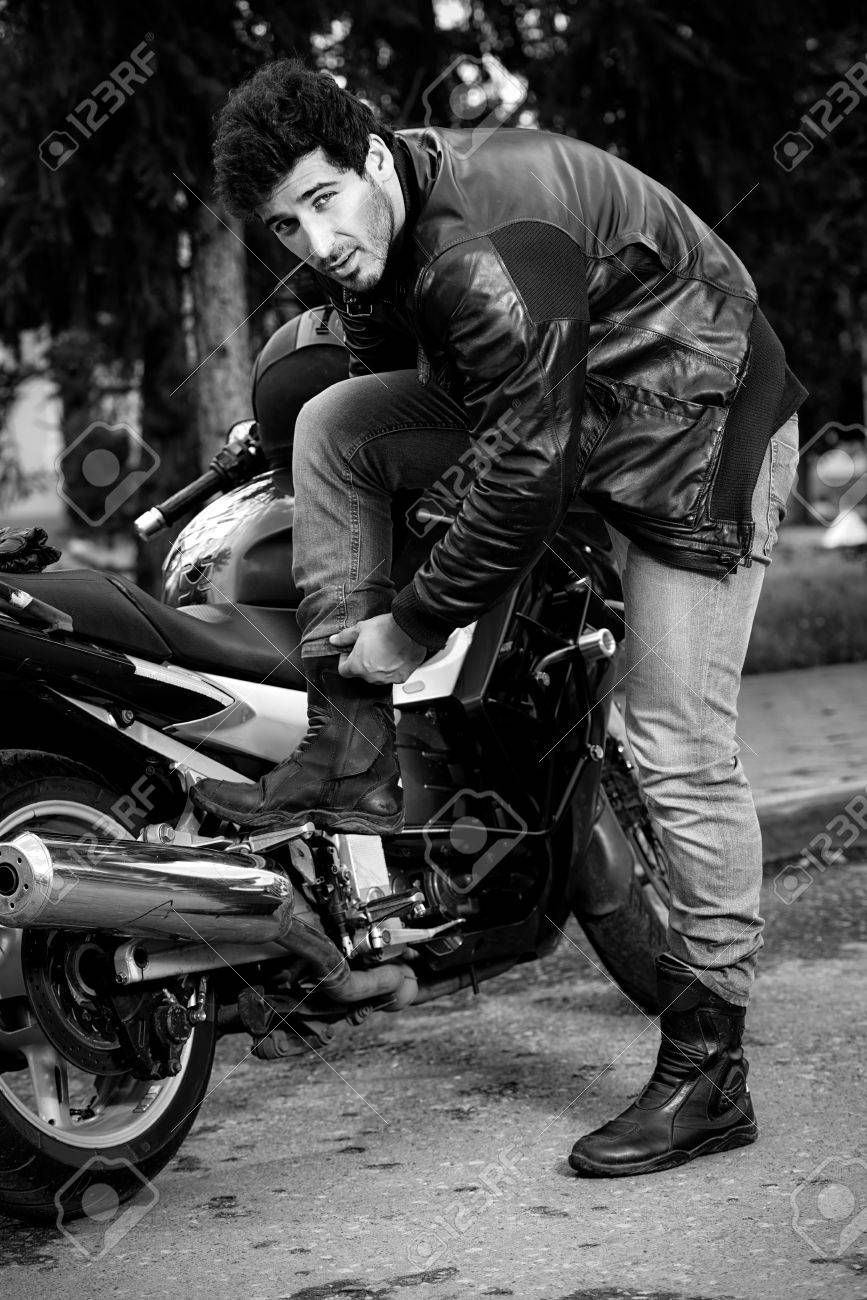 65894638-portrait-noir-et-blanc-d-un-motard-homme-sexy-portant-des-jeans-et-veste-en-cuir-debout-détendue-pa.jpg